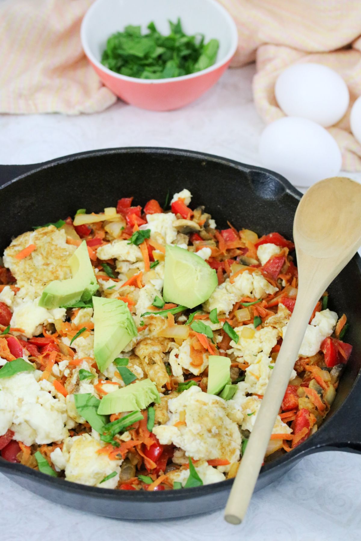 Cast-iron skillet with vegetables like carrots and peppers and scrambled eggs.