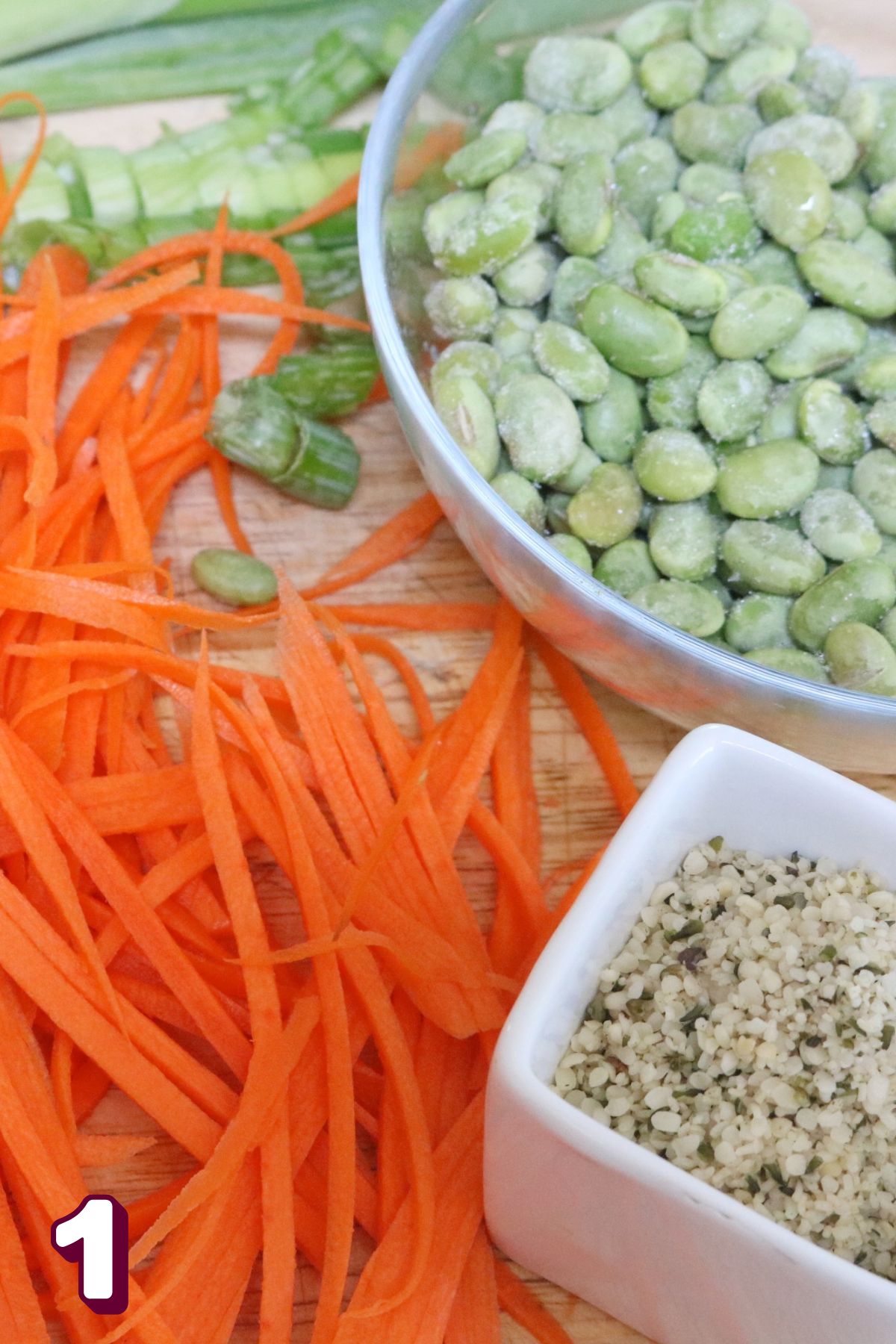 Carrots, edamame, and hemp hearts on a cutting board.