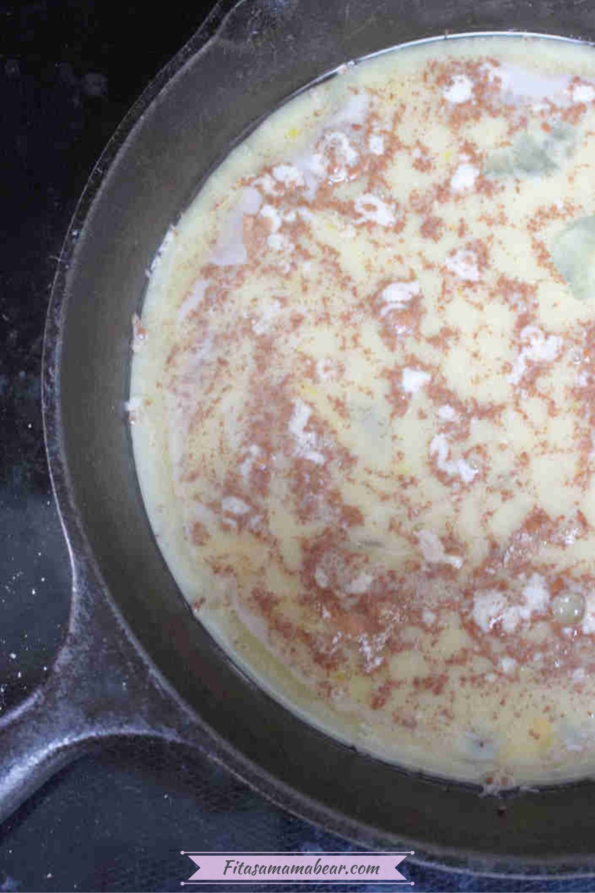 Raw egg white pancake with cinnamon in a cast iron pan.