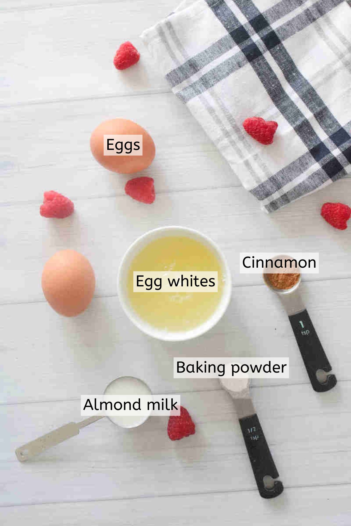 Eggs, egg whites, cinnamon, and baking powder in measuring cups with text labels over top.