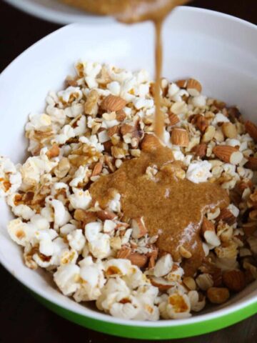 Caramel sauce being poured over popcorn and nuts.