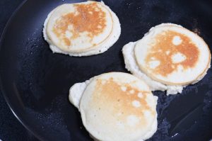 Inprocess image for yogurt pancakes. Flipping pancakes in pan