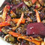 Roasted carrots, beets and Brussels sprouts on a tinfoil lined pan topped with sesame seeds