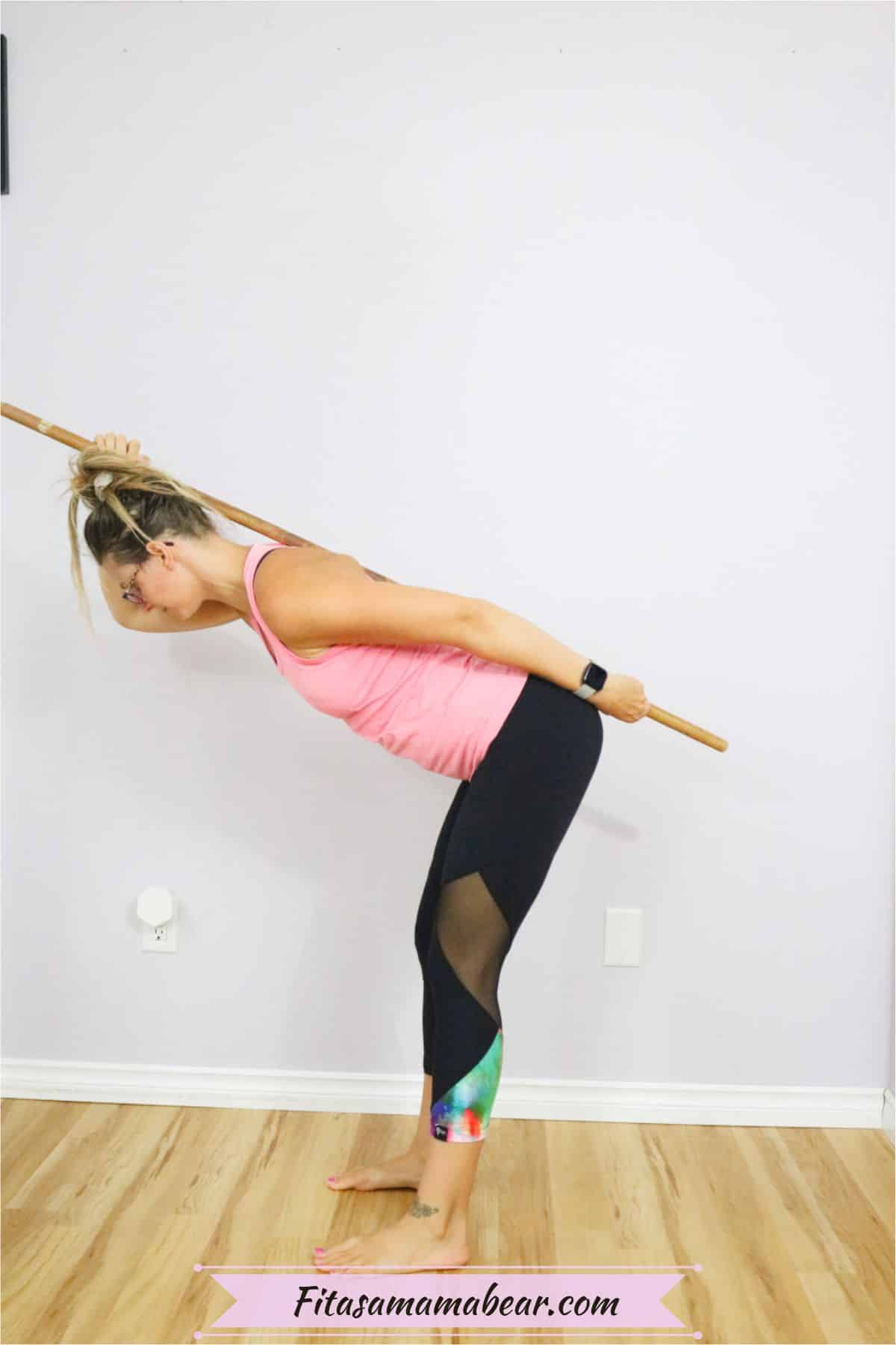 Woman in pink tank top and black pants learn how to perform a hip hinge with a dowel on her back
