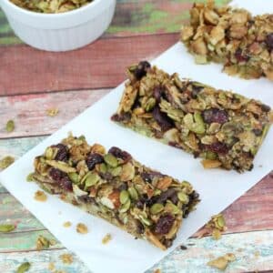Three granola bars with dried fruit in them on parchment paper.