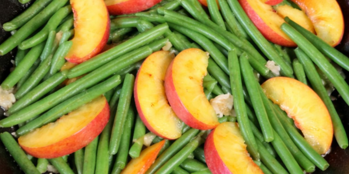 Green beans and peaches in a cast iron pan.