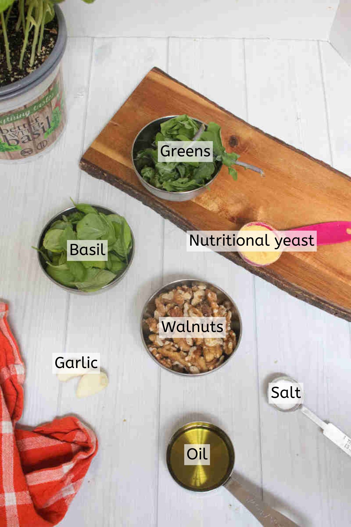 Ingredients to make pesto sauce without pine nuts like spinach, basil, and walnuts in measuring cups with text labels over top.
