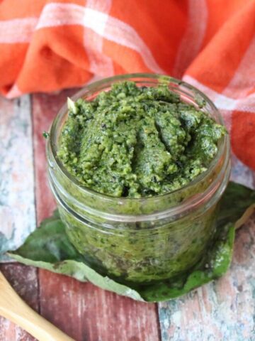 homemade basil pesto sauce in a mason jar with a wooden spoon
