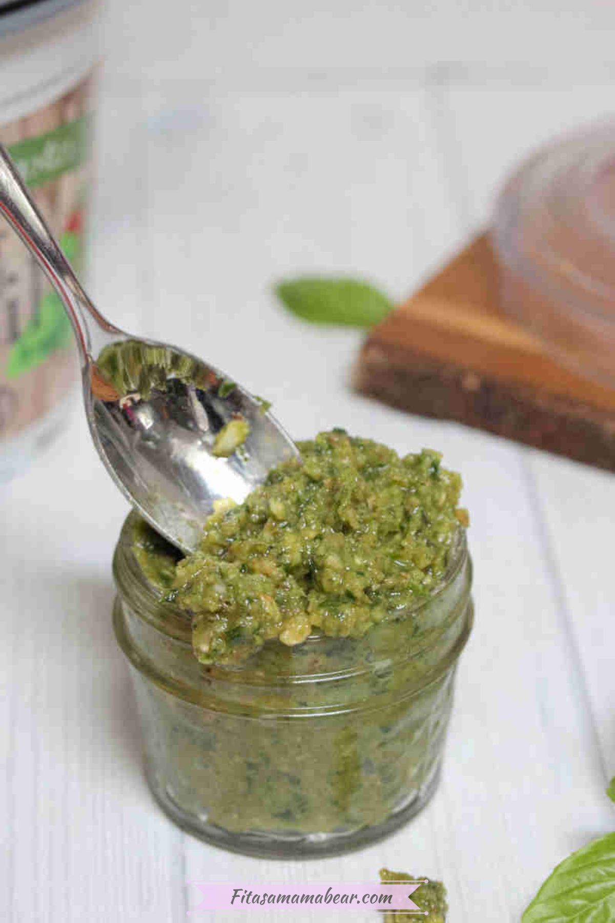Dairy-free pesto sauce in a mason jar with a spoon in the jar.
