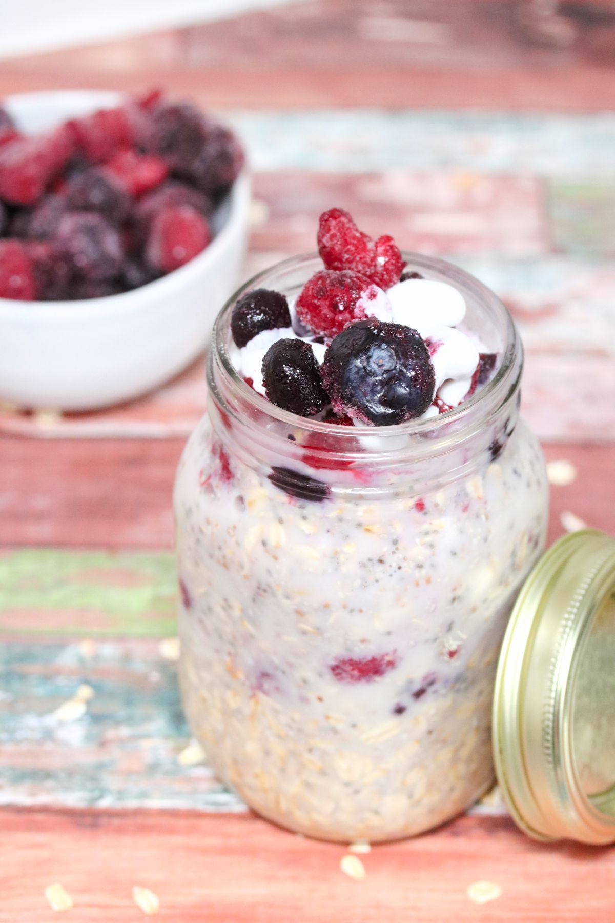 Dairy-free overnight oats with berries in a  mason jar and more berries behind it.