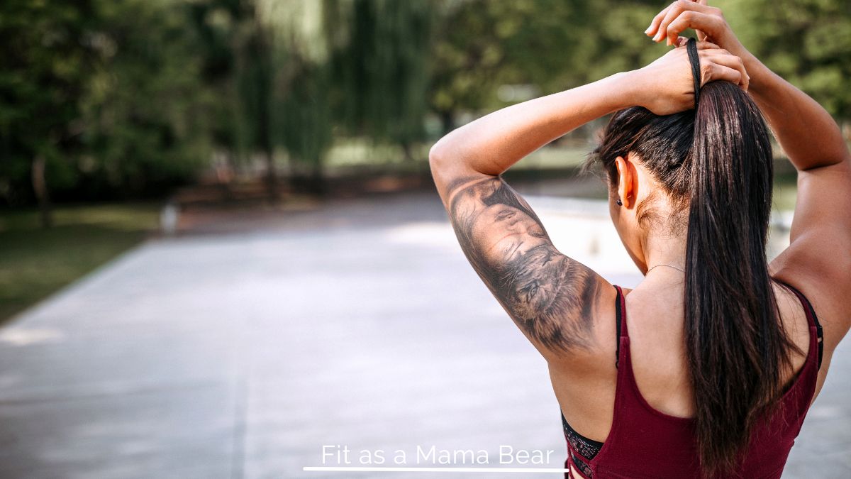 Woman putting a ponytail in her hair.
