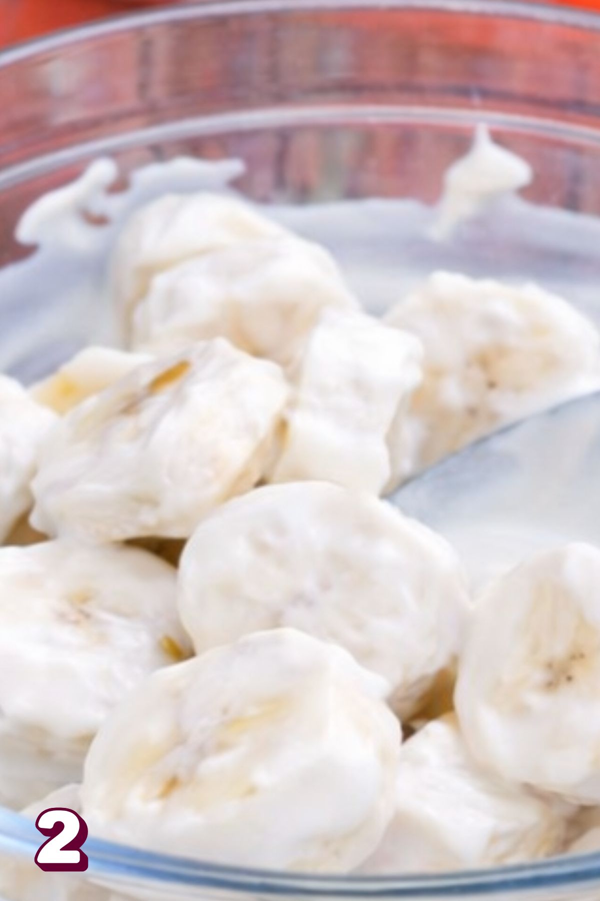 Bananas in a glass bowl coated in yogurt.