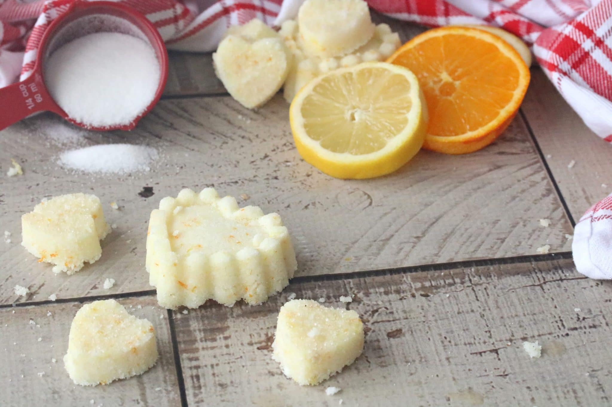 Homemade sugar scrub cubes in heart shapes with lemon and orange in the background