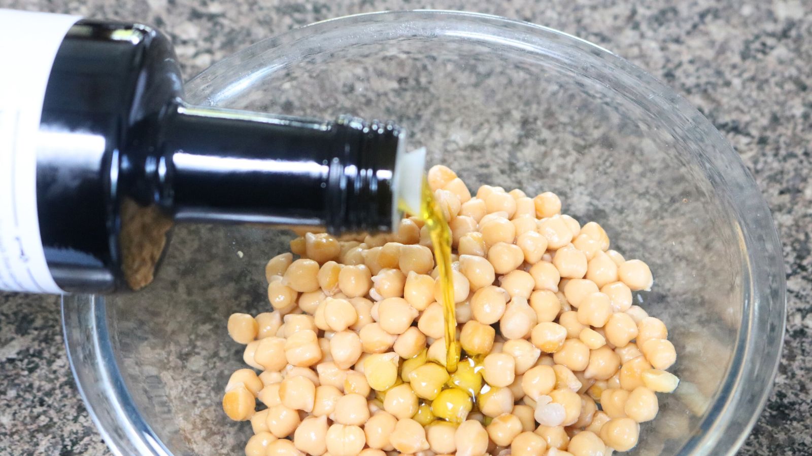 Oil being poured into a bowl of chickpeas.
