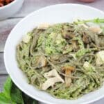 White bowl with checken pesto pasta in it on soba noodles.