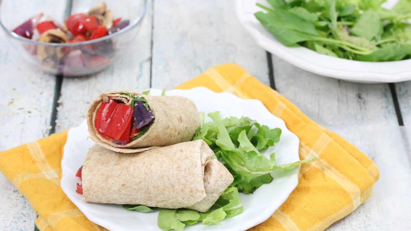 Vegetable and hummus wrap sliced and stacked on a  plate with lettuce.