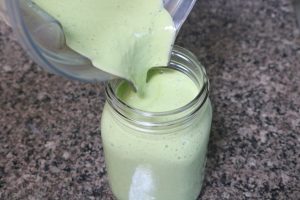 Key lime protein smoothie being poured into a mason jar