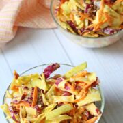 Dairy-free coleslaw in a glass bowl with a peach linen behind it.