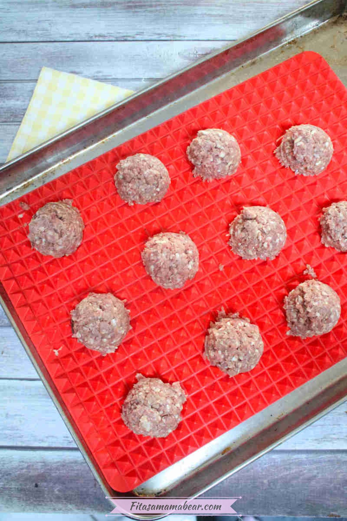 Uncooked gluten-free teriyaki meatballs on a silicone mat on a pan.
