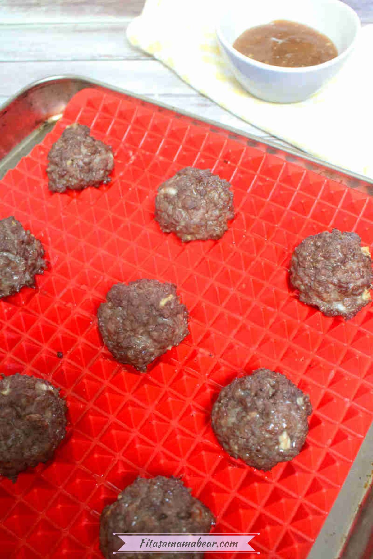 Gluten-free teriyaki meatballs on a silicone mat on a pan.