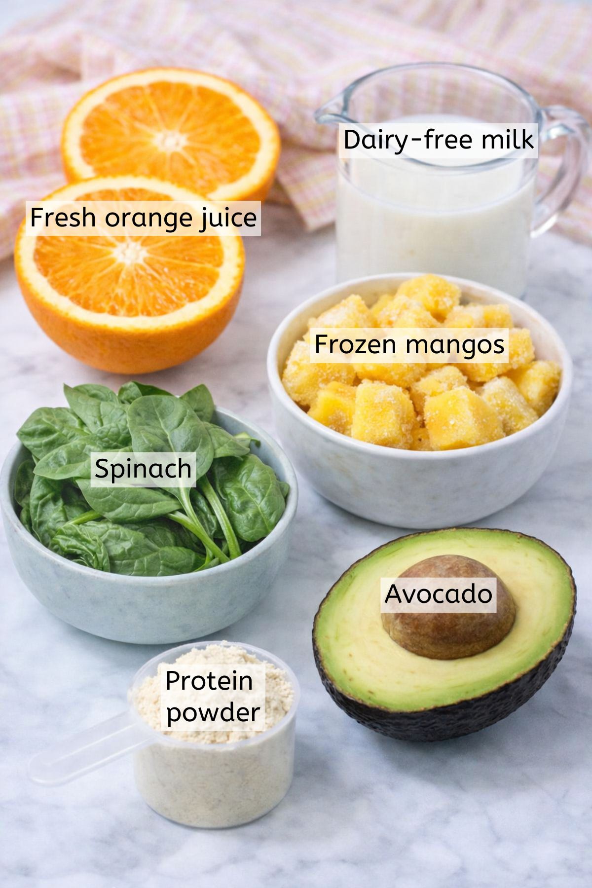 Mango, avocado, spinach, protein powder, and milk in cups with text labels over top.