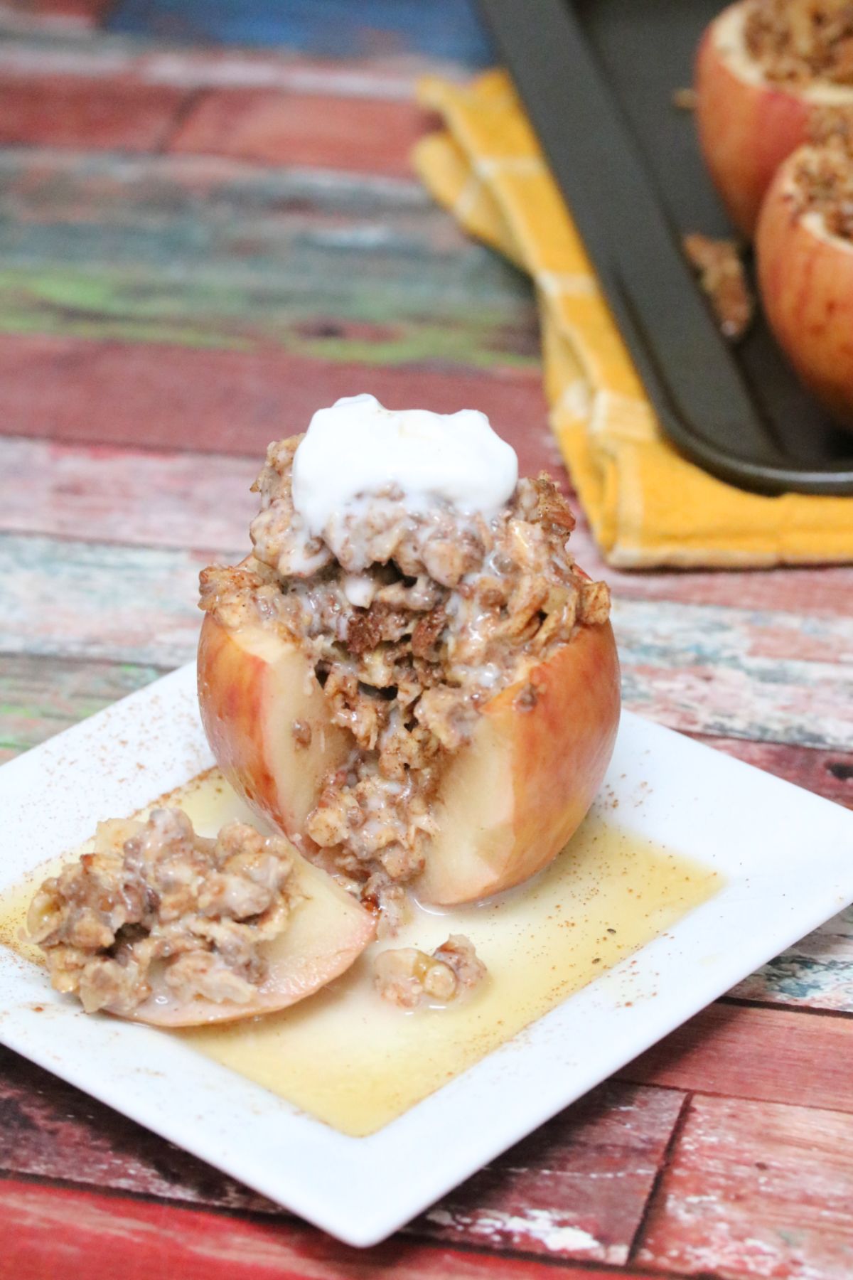 Baked apple stuffed with oatmeal with a slice cut out on a white plate with maple syrup.