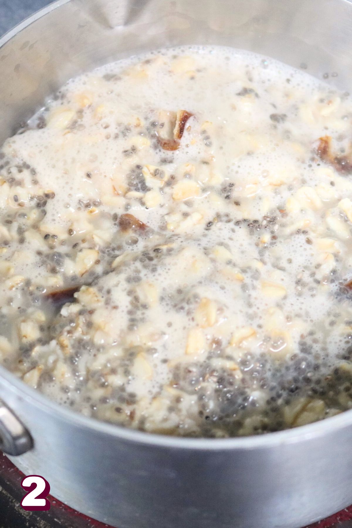 Oatmeal with milk and chia seeds cooking in a small pot.