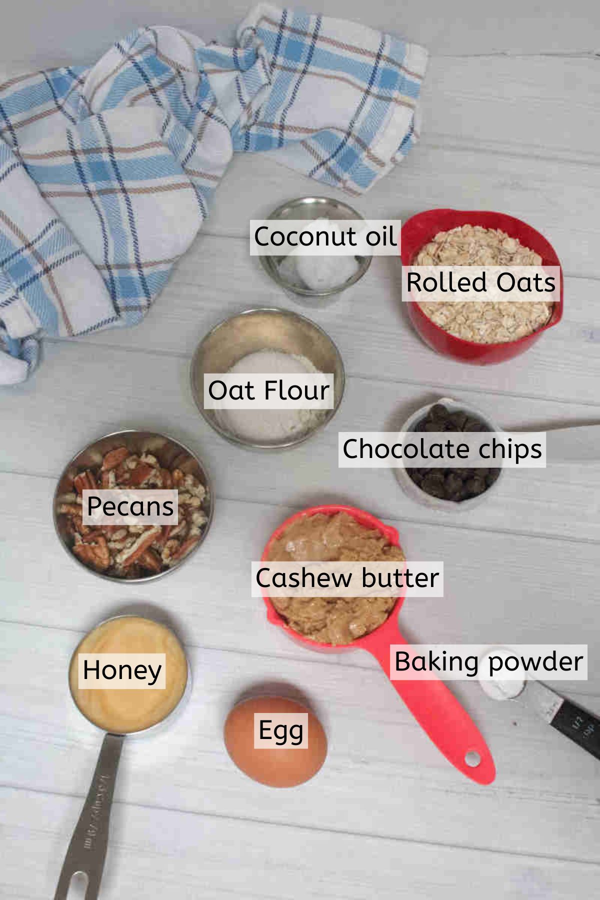 Multiple ingredients to make cashew cookies in measuring cups with text labels over top.