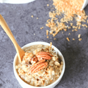 White ramekin with oatmeal topped with pecans and a wooden spoon in the ramekin.