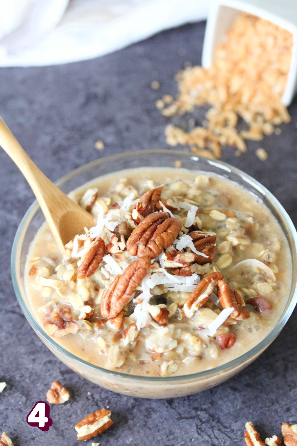 Pecan protein oatmeal in a glass bowl topped with pecans and coconut.