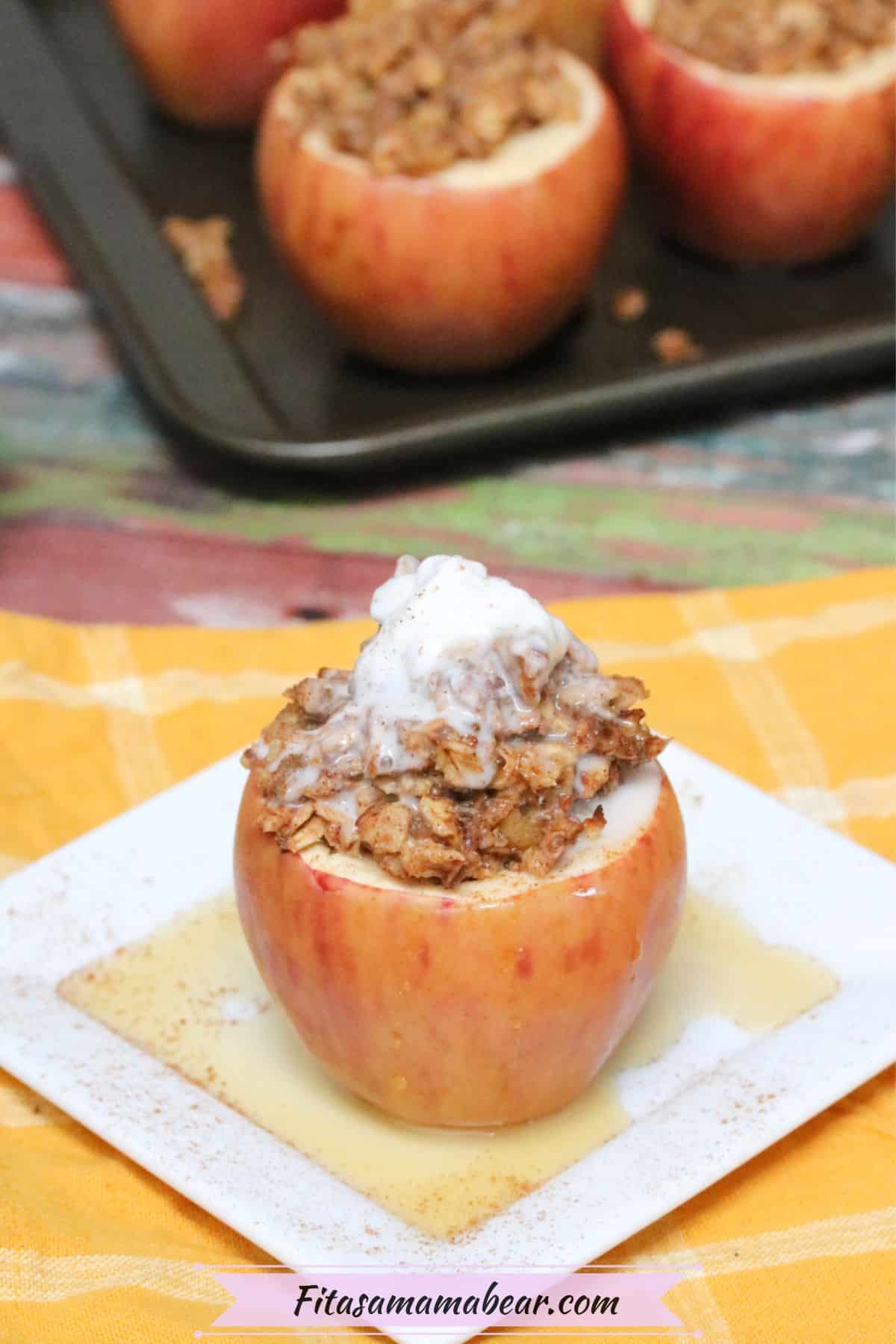 Apple stuffed with oatmeal and topped with whole 30 whipped cream on a white plate with maple syrup on it and more apples in a pan behind them.
