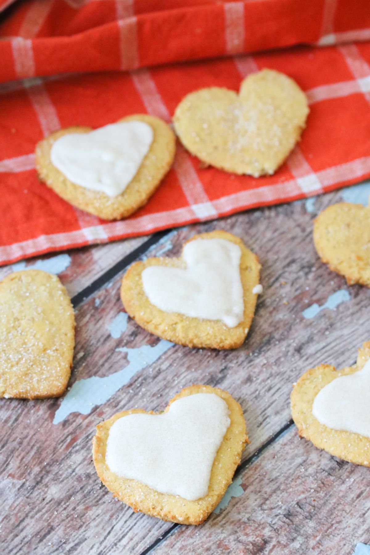 Heart shaped coconut flour sugar cookies, some of them iced on an orange linen.