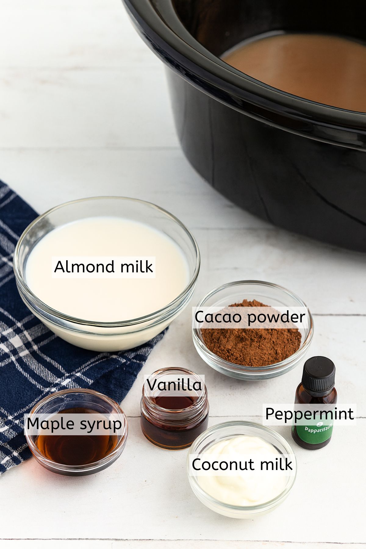 Multiple ingrdients like coconut milk, cacao, and maple syrup in glass bowls with text labels over top.