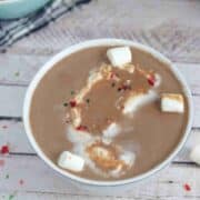 White cup with paleo hot chocolate, candy canes, and marshmallows in it.
