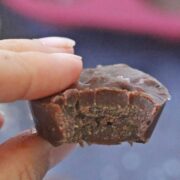 Two fingers holding a piece of keto chocolate fudge up close with a bit out of it.