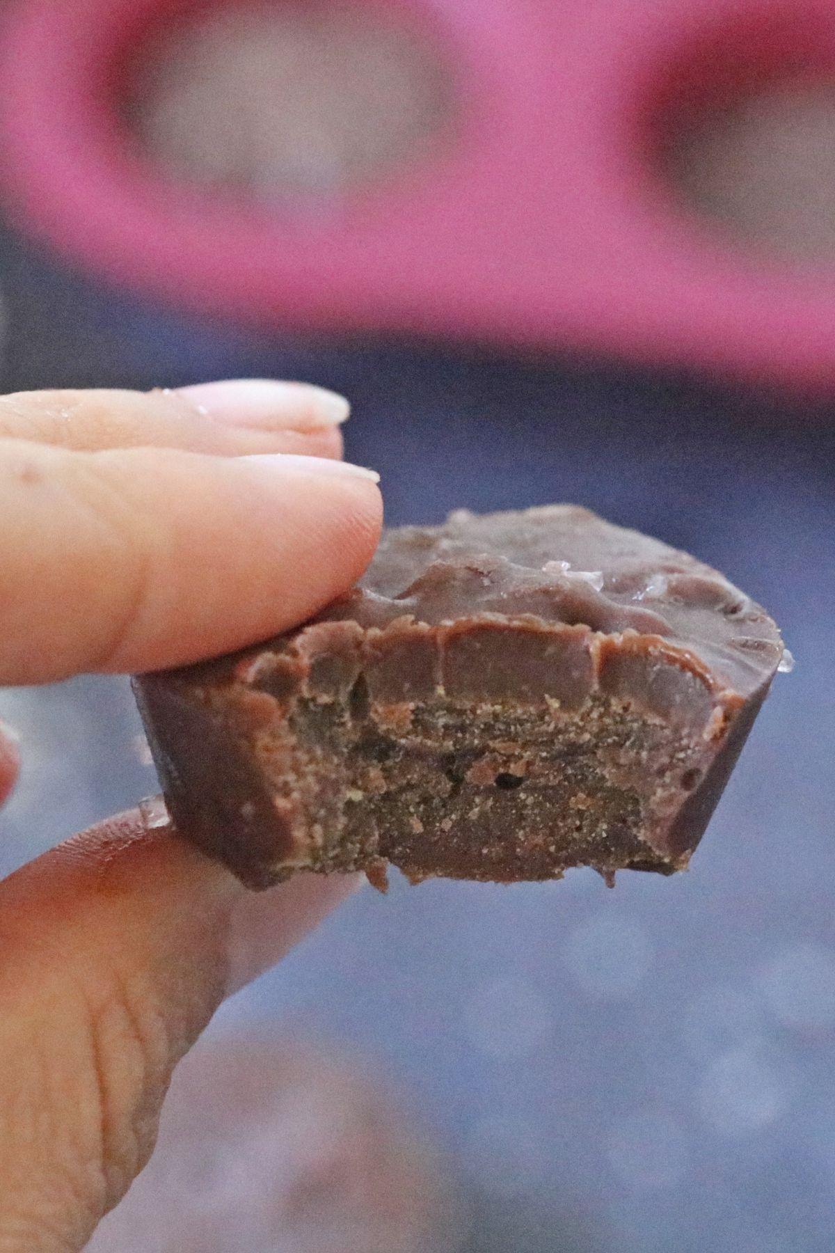 Two fingers holding a piece of keto chocolate fudge up close with a bit out of it.