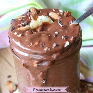 Mason jar overflowing with chocolate banana nice cream topped with cacao nibs, bananas, almonds and a spoon