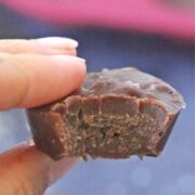 Two fingers holding a piece of keto chocolate fudge up close with a bit out of it