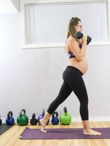 Pregnant wonamn in sports bra and tights holding dumbbells at her ches in a split stance position