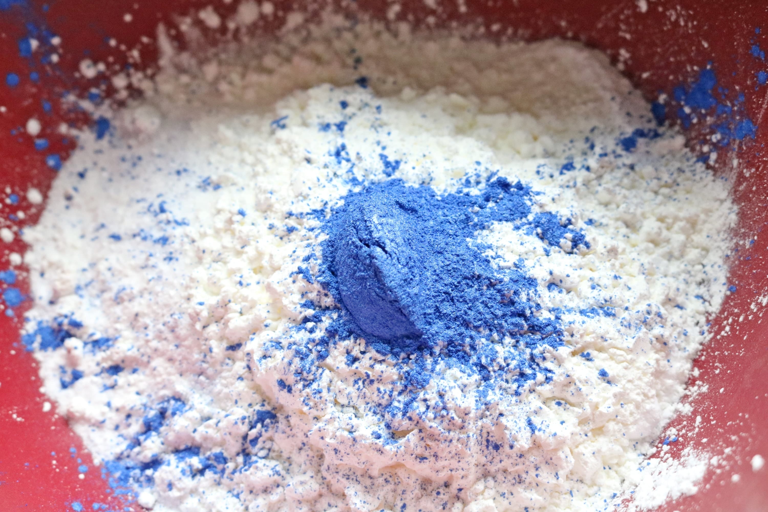 White and blue powders being mixed in a blue bowl