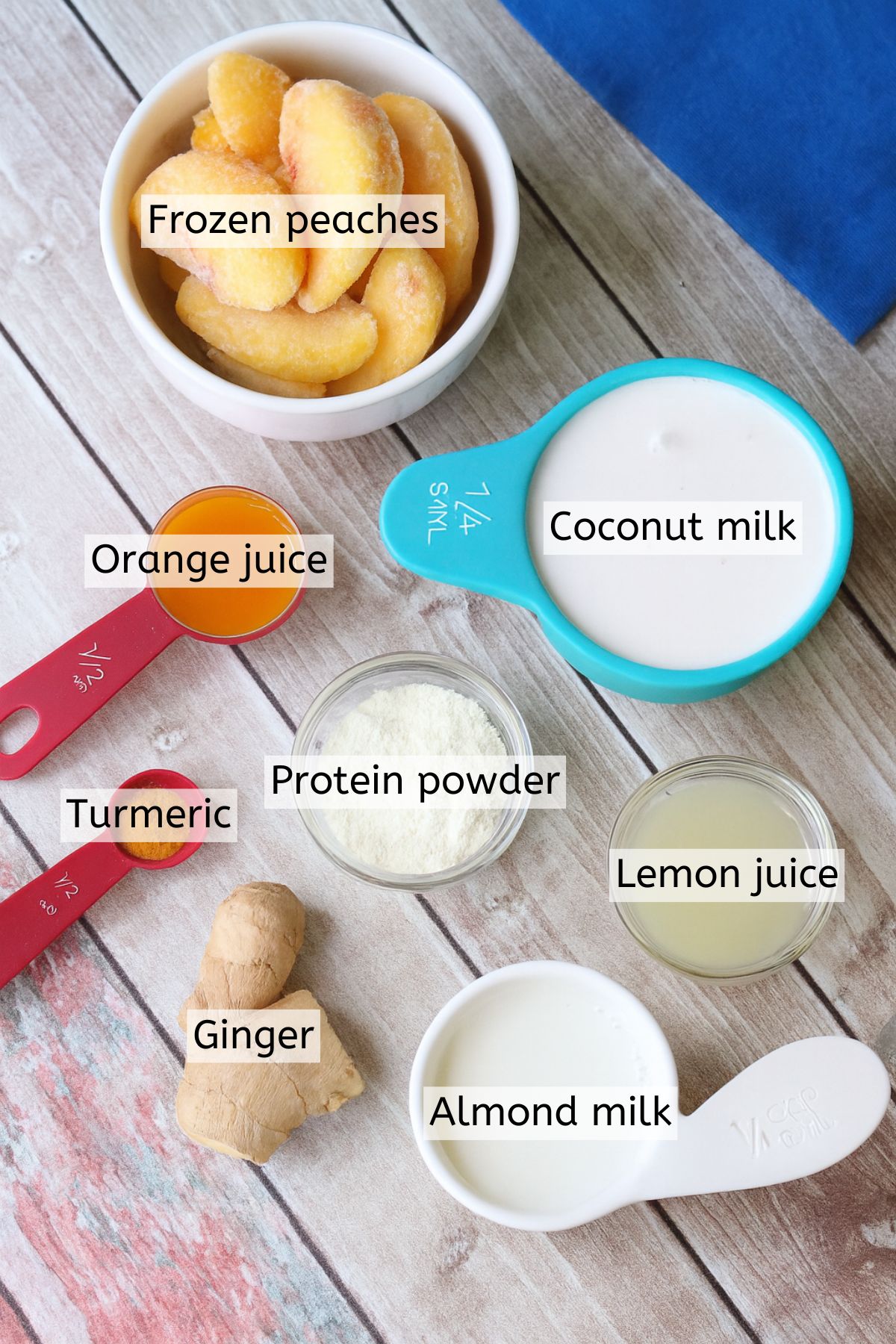 Multiple ingredients like protein powder, turmeric, ginger, and milk in measuring cups with text labels over top.