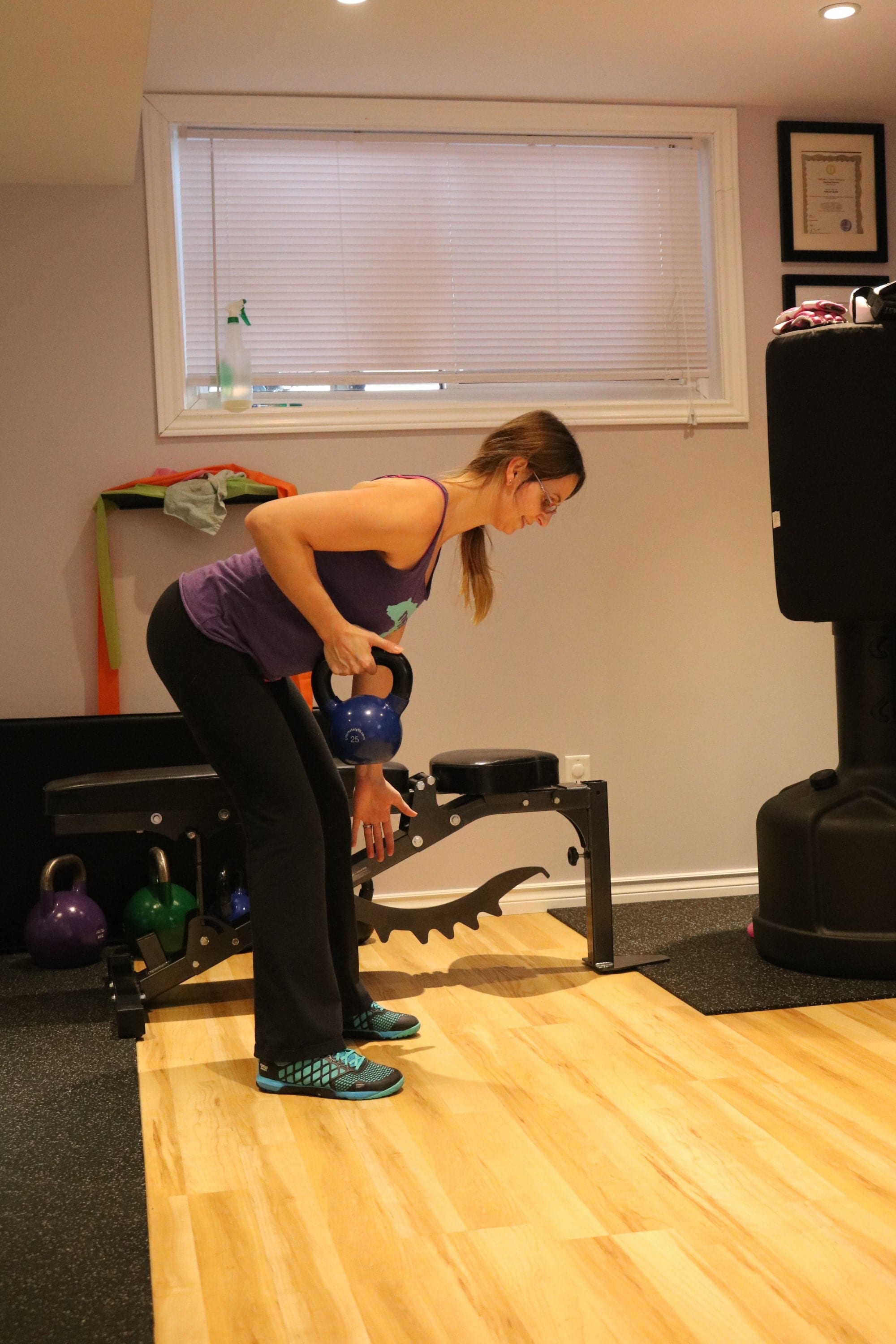 Woman in the gym performing a one arm kettlebell row