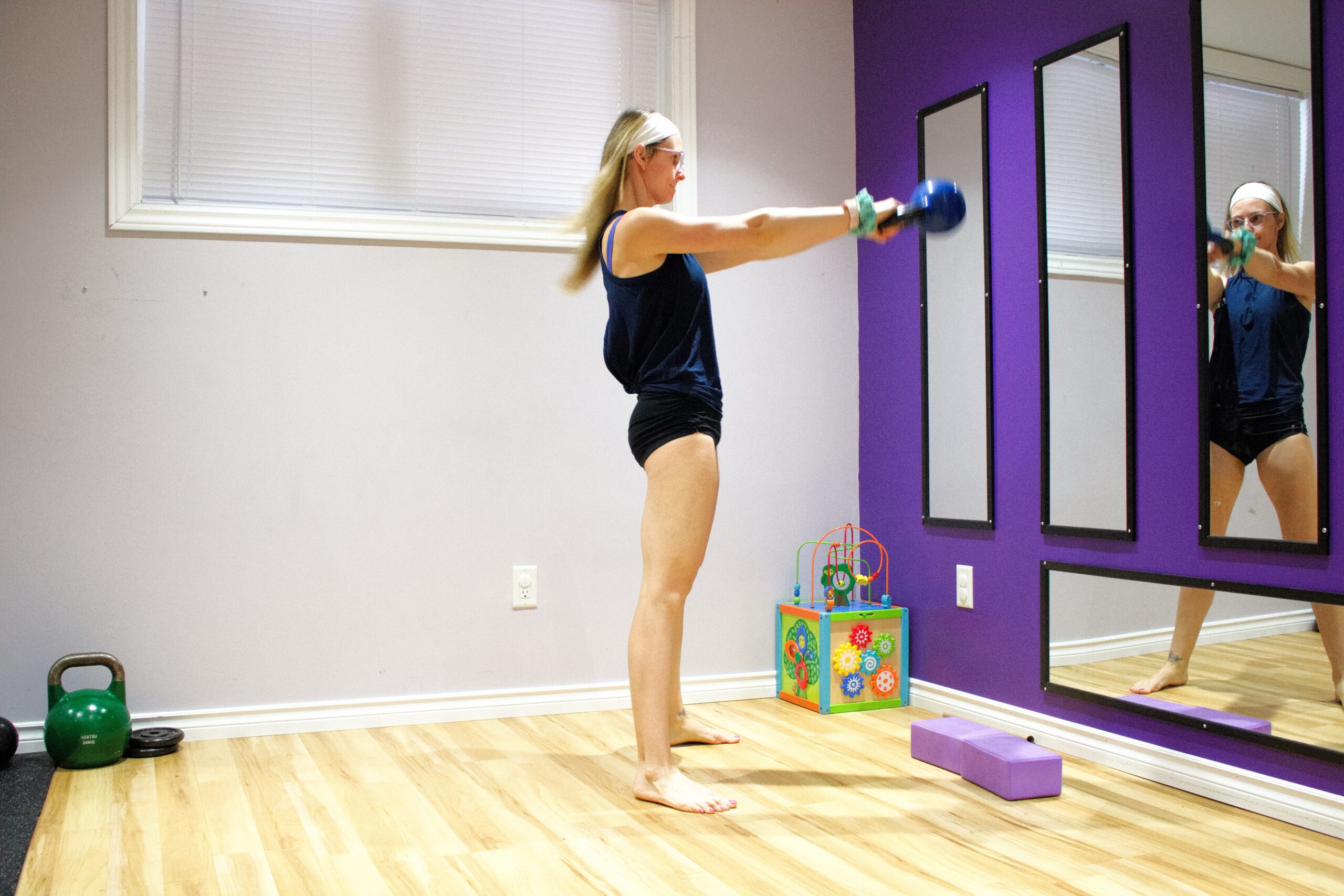 woman in black shorts and blue shirt performing a kettlebell swing