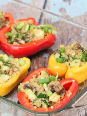 red and yellow quinoa vegan stuffed peppers in a glass baking tray.