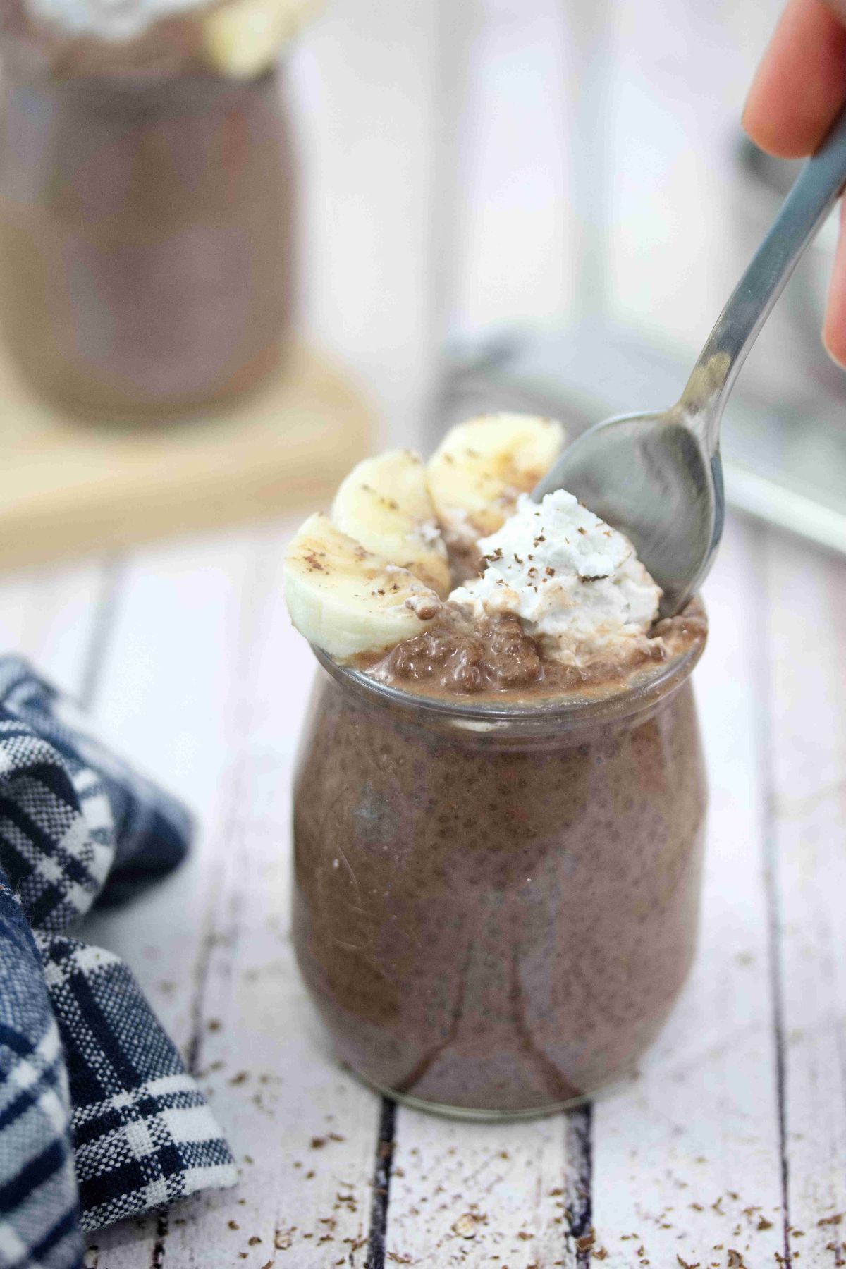Chocolate banana chia pudding in a mason jar with a spoon.