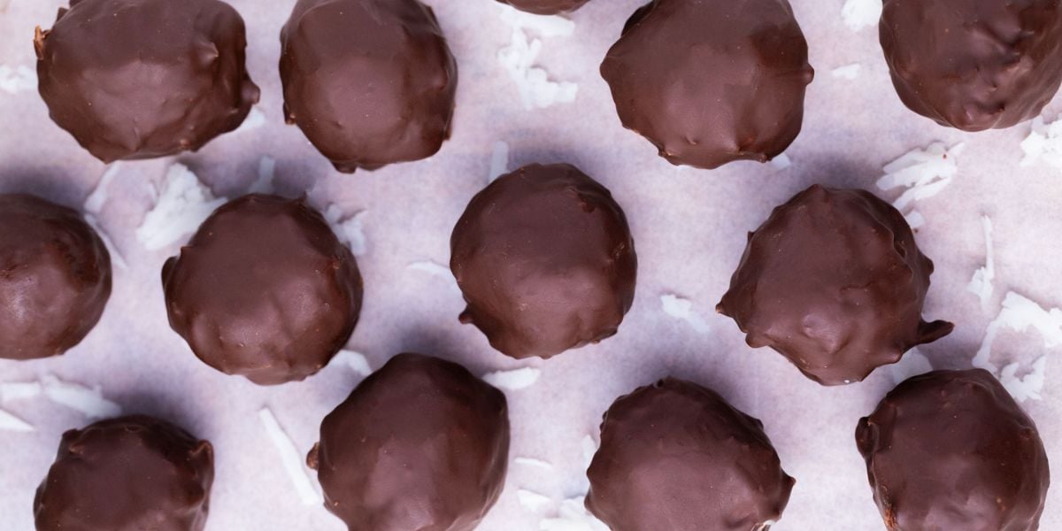 No-bake chocolate covered protein ball on parchment paper.