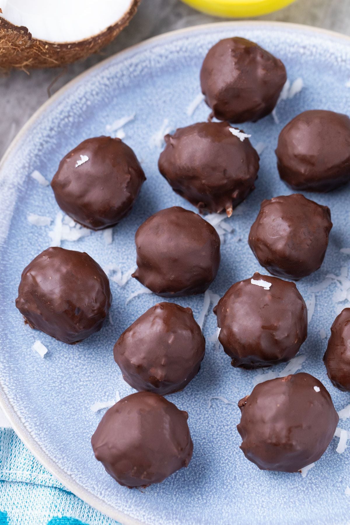 Chocolate coated coconut protein balls on a blue plate.