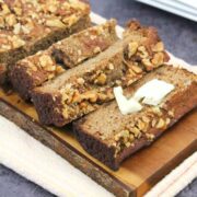 sugar-free banana bread cut in slices on a cutting board with one slice topped with dairy-free butter