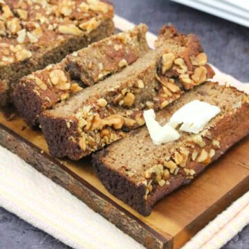 sugar-free banana bread cut in slices on a cutting board with one slice topped with dairy-free butter