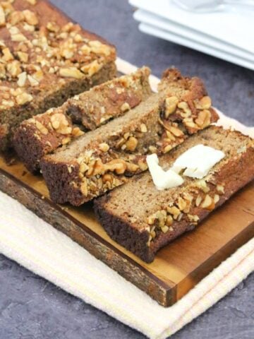sugar-free banana bread cut in slices on a cutting board with one slice topped with dairy-free butter